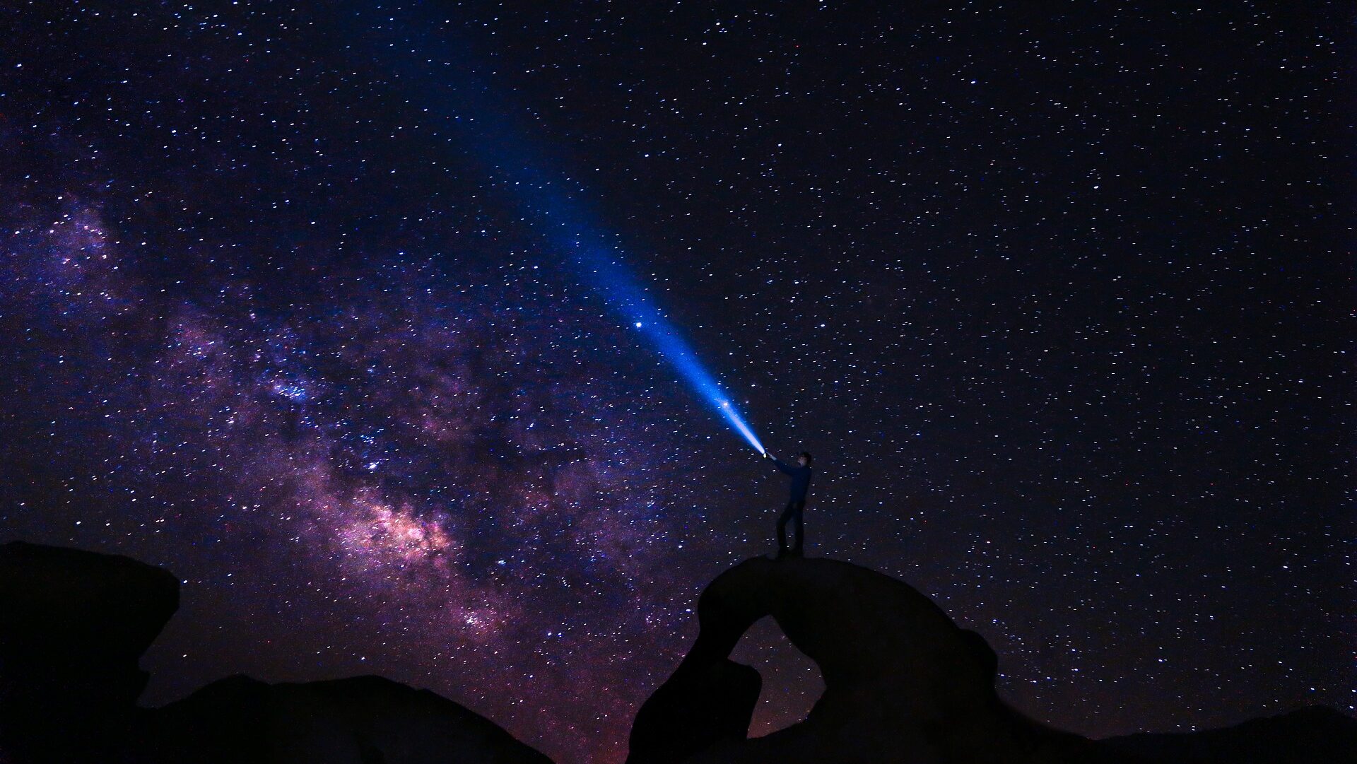 A person with a flashlight looking at the night constellations.