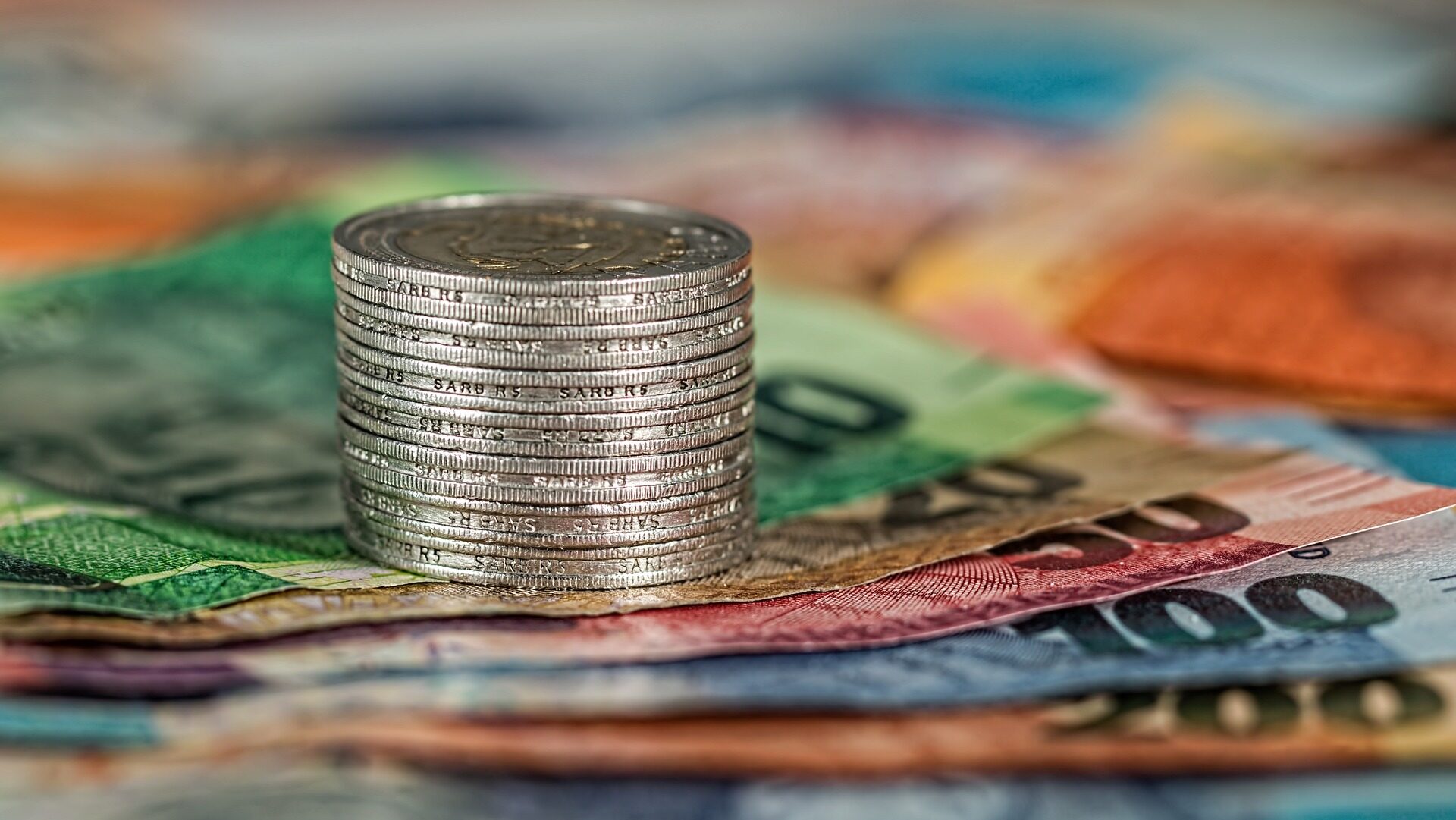 Stack of silver coins on top of bank notes.