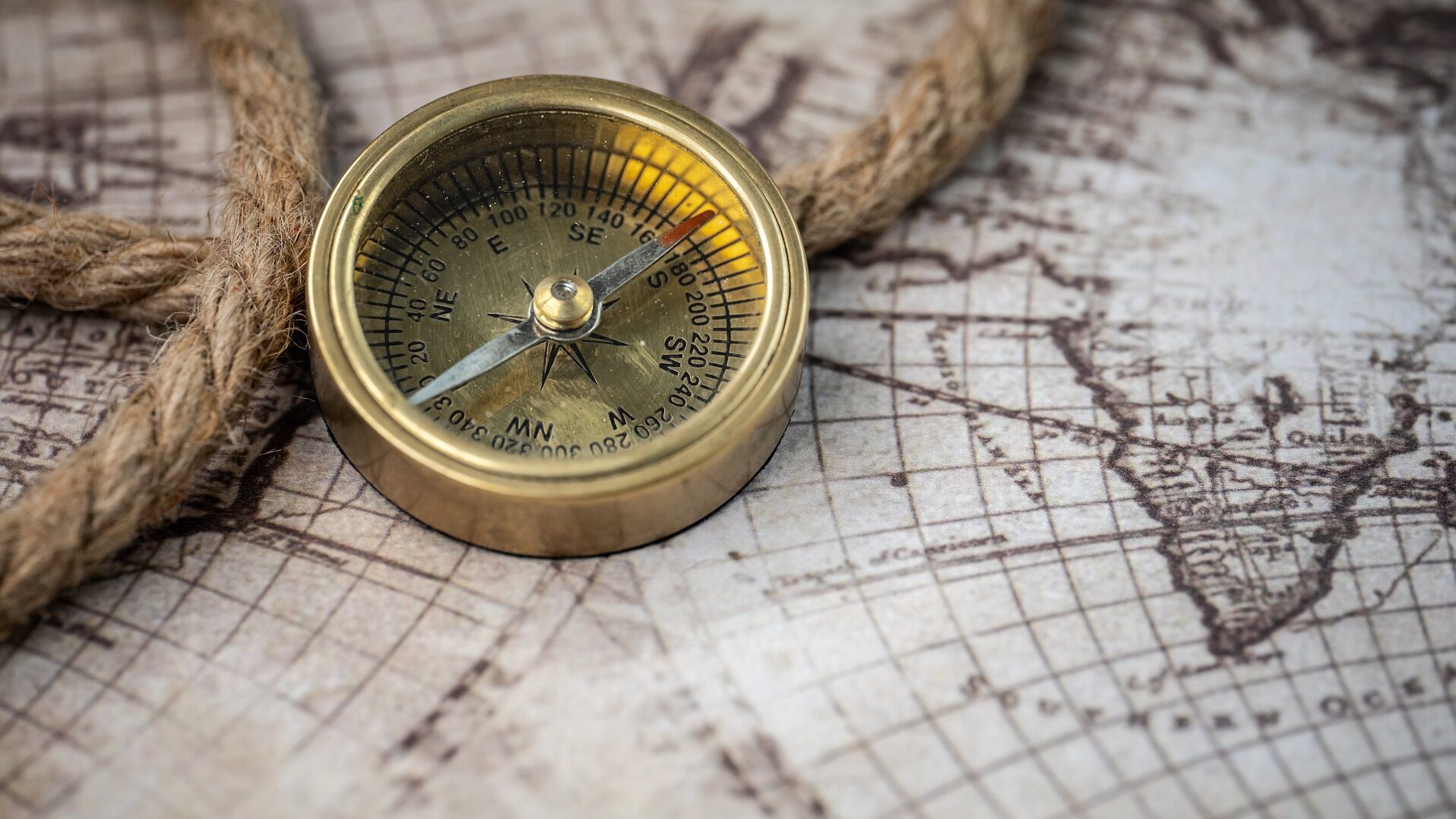 Gold compass on a map with rope.