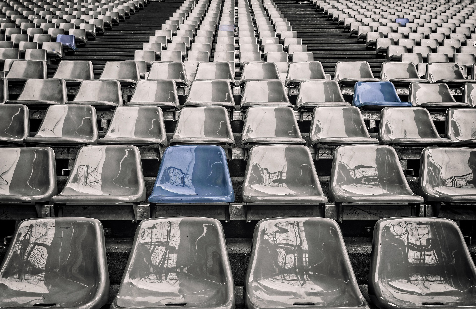 Rows of silver stadium seats with blue chairs in spots