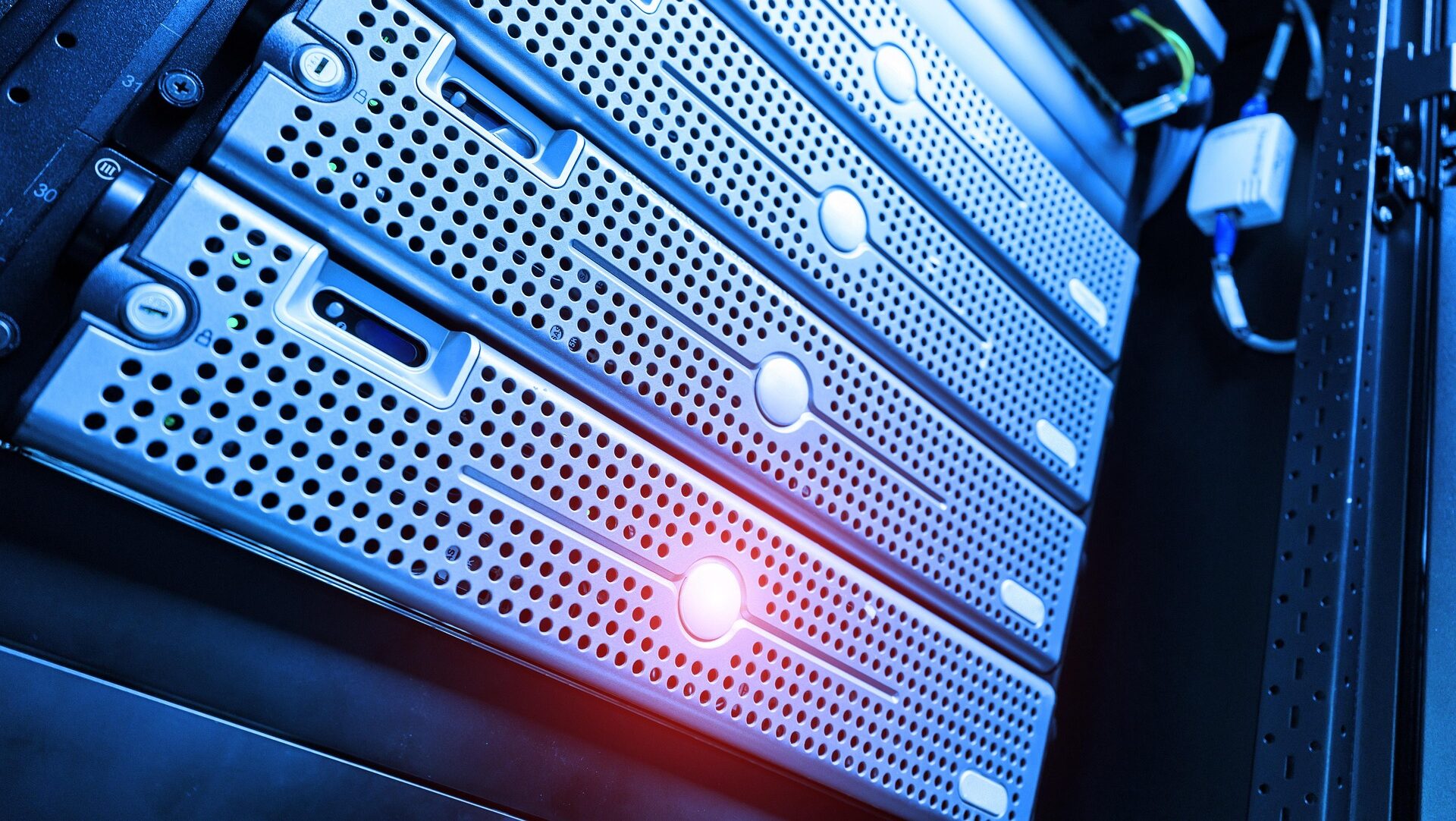 Computer servers on a rack with a red light shining.